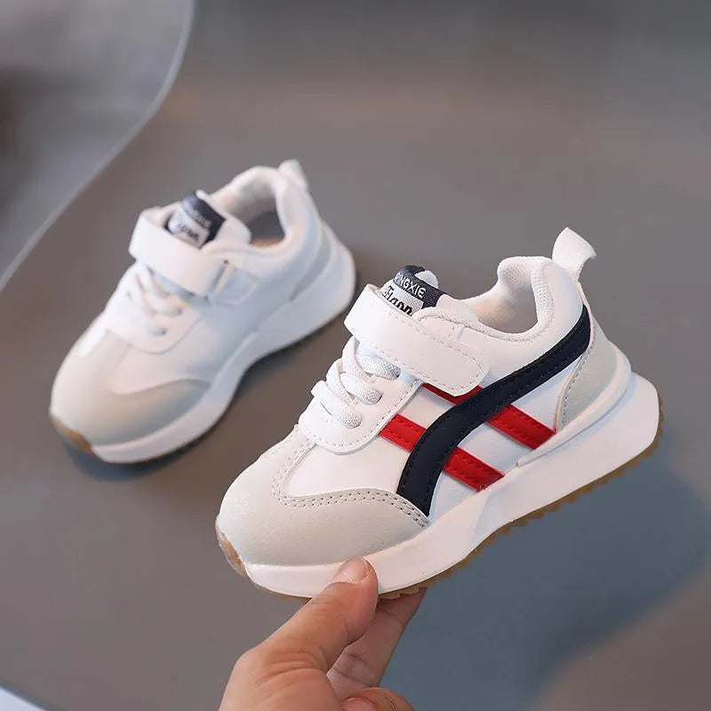 Children's white velcro sneaker with synthetic leather upper and rubber sole on a neutral background.