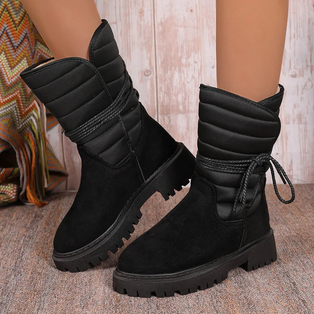 Women's black chunky heel snow boot with lace-up design and suede upper on a white background.