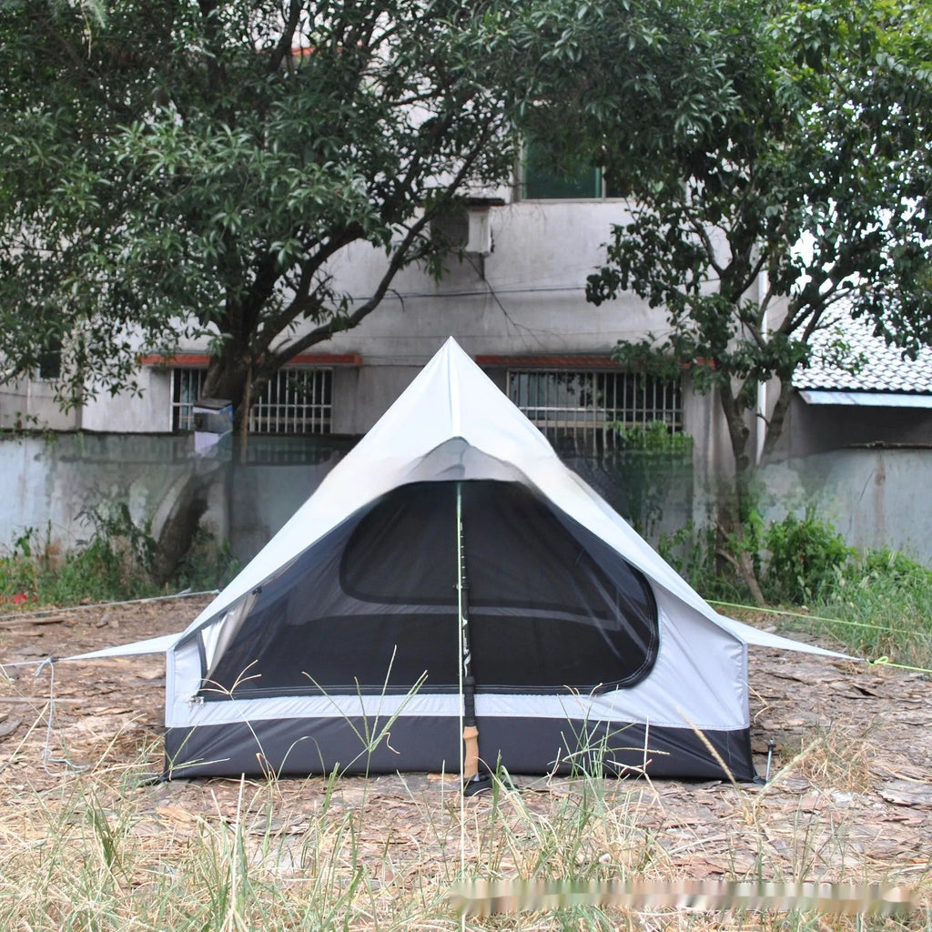 Brown A-line hiking tent set up with trekking poles in a forest clearing.