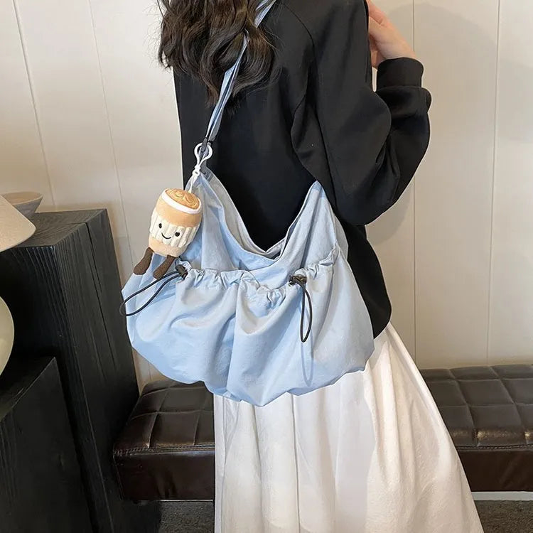 Ultra-light pleated crossbody student cloth bag in soft polyester, showing split pocket and internal phone storage.