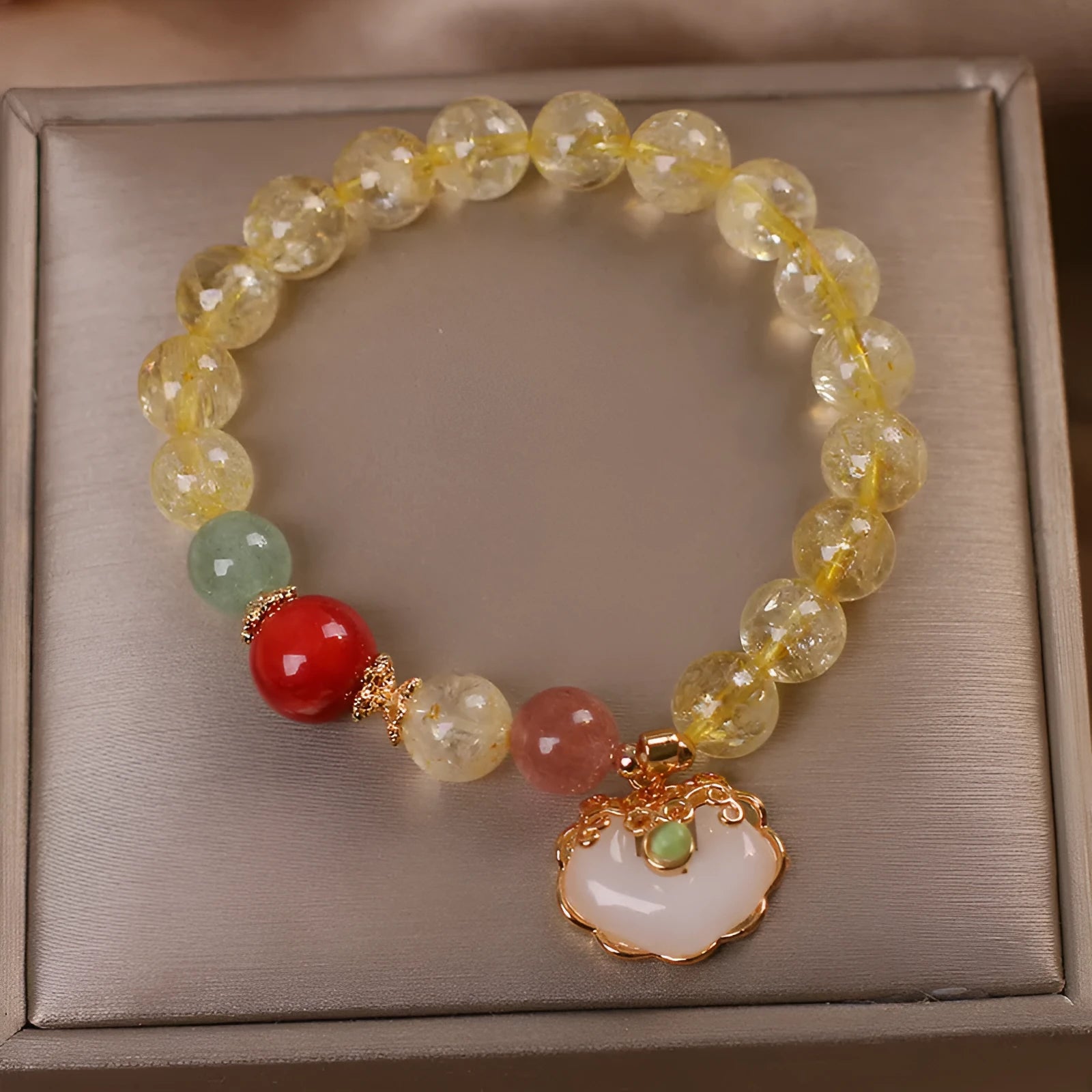 Close-up of a women's adjustable bracelet with a yellow citrine jade ruyi pendant on an alloy chain.