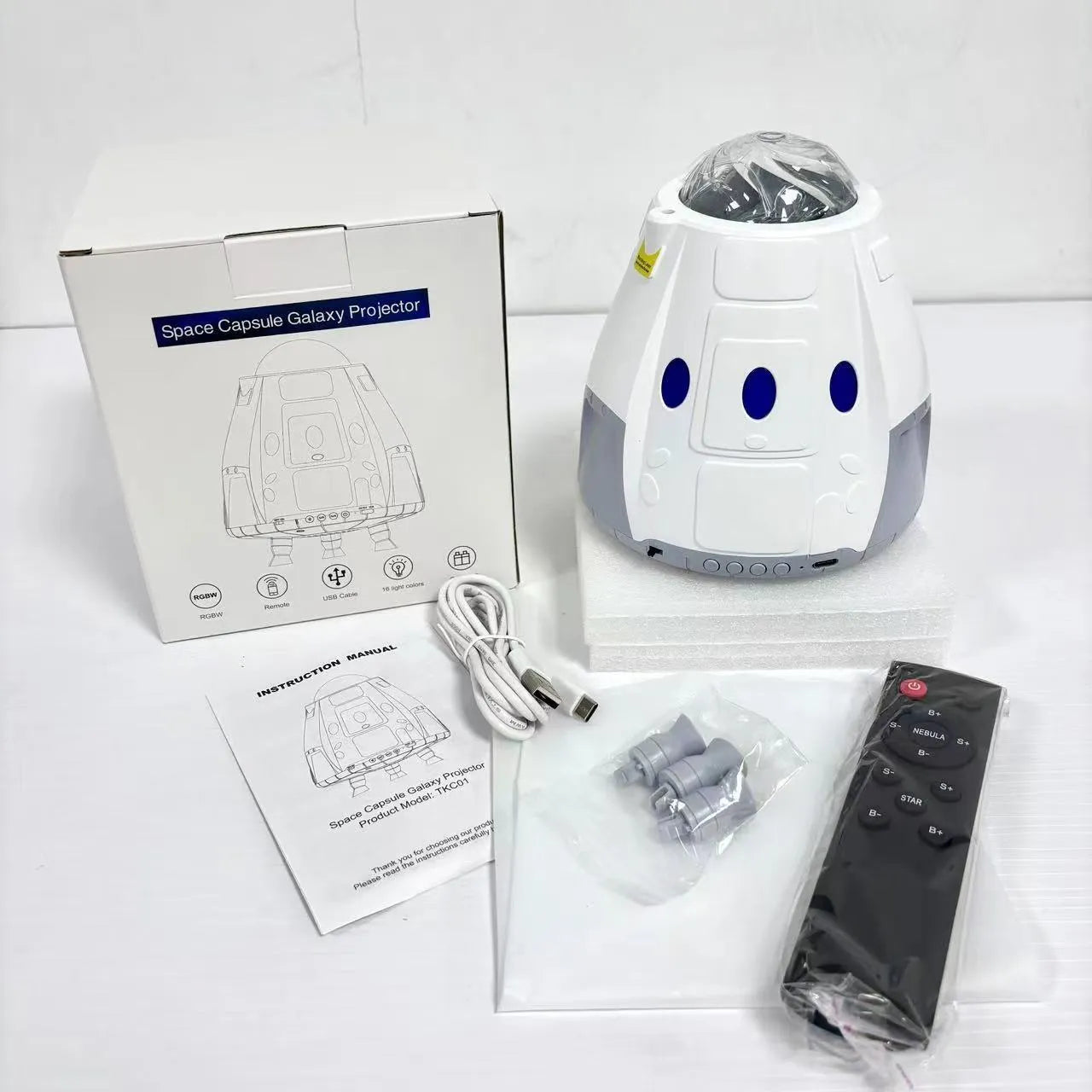 Creative USB space capsule starry atmosphere projection lamp in Space White with remote control on a bedside table
