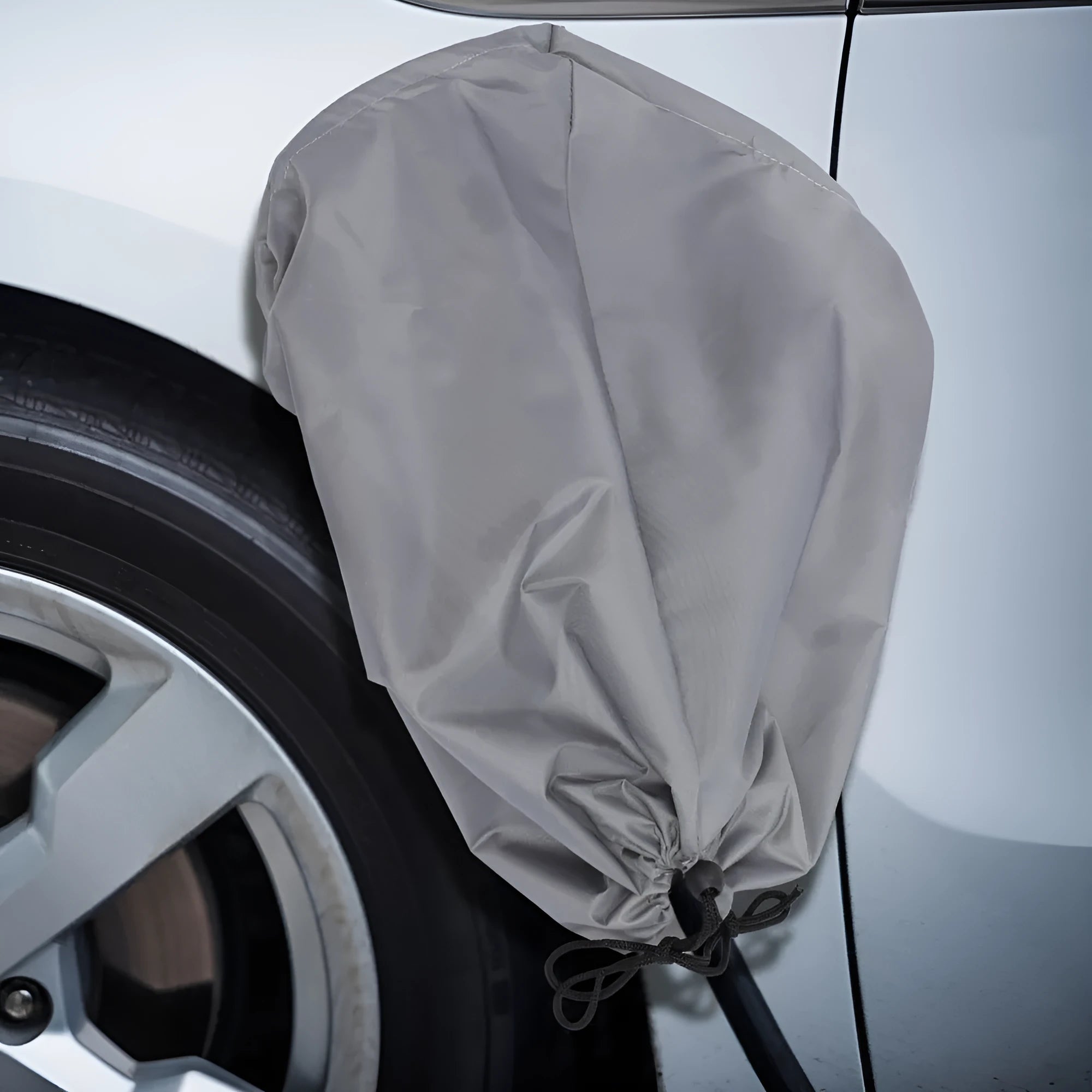 Grey waterproof drawstring cover for electric car charging port on a vehicle.