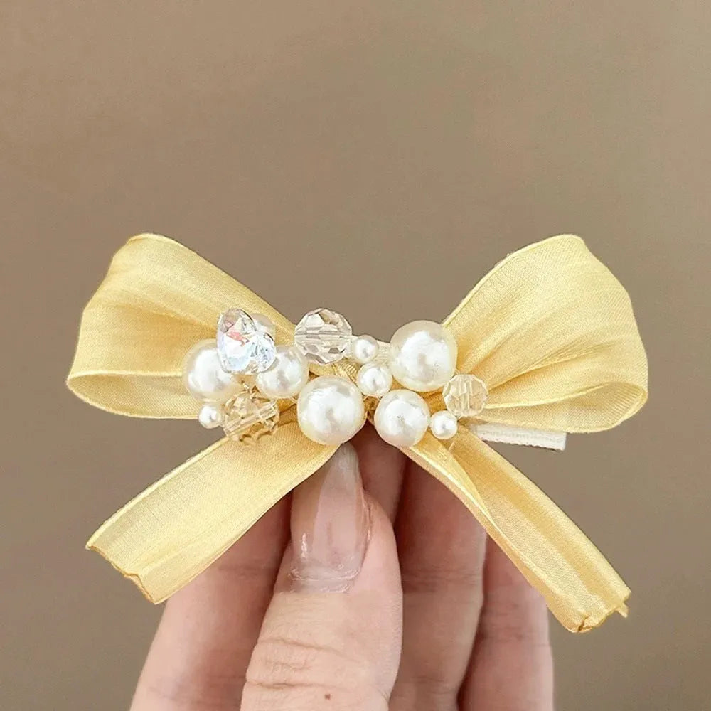 Yellow bow barrette with rhinestone and pearl on plastic duckbill clip for women