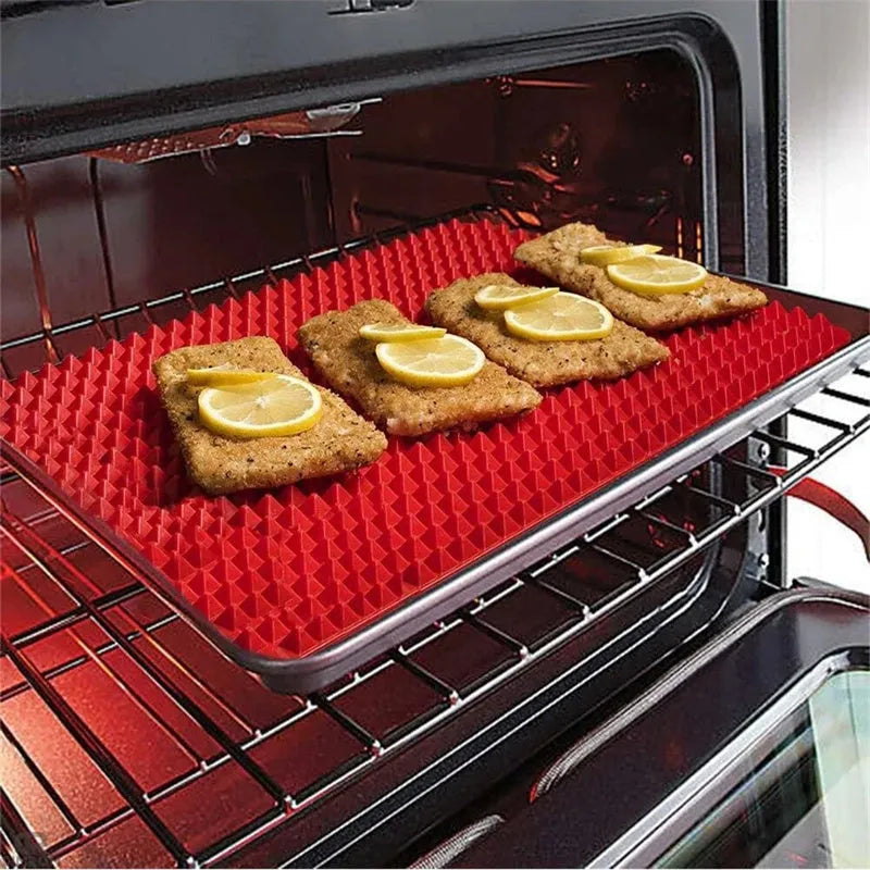 Red non-stick silicone pyramid cooking mat with grid on a baking tray for oven or BBQ use