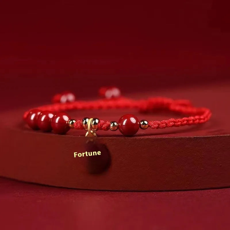 Cinnabar birth year braided rope bracelet with round bead blessing card in wine red colour on a plain background.