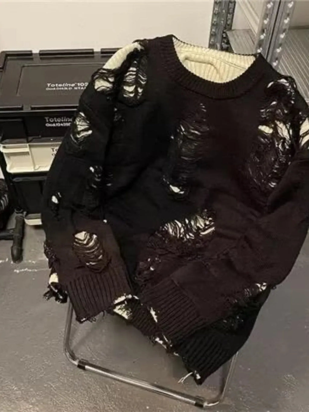 Men's black ripped pullover sweater with animal pattern and tassels on gray background