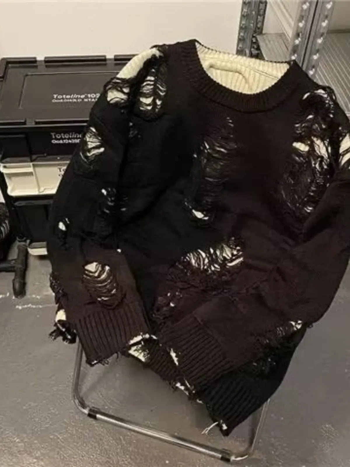 Men's black ripped pullover sweater with animal pattern and tassels on gray background