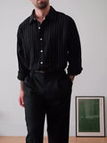 Man wearing a black pinstriped button-down long sleeve shirt with a collar.