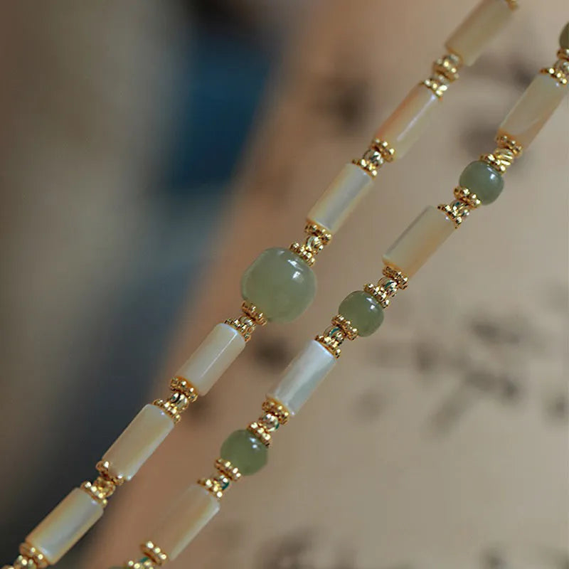 Natural Hetian jade white lip shell round bead bracelet for women on a neutral background