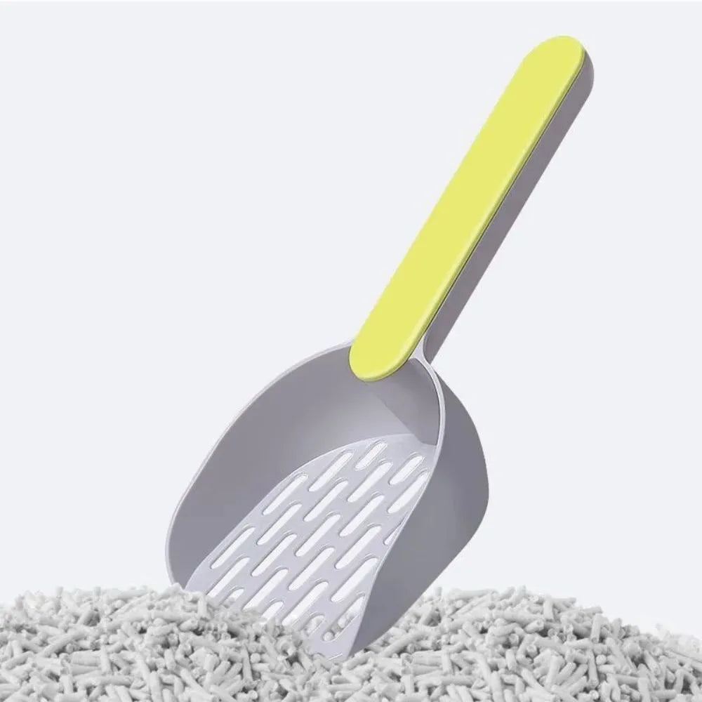 Plastic cat litter shovel in blue, green, and pink colours on a clean surface