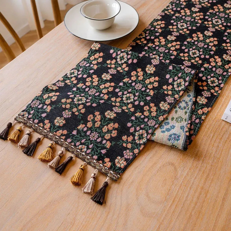 Dark blue striped Nordic style table runner with bouquet tassel decoration laid flat on a table.