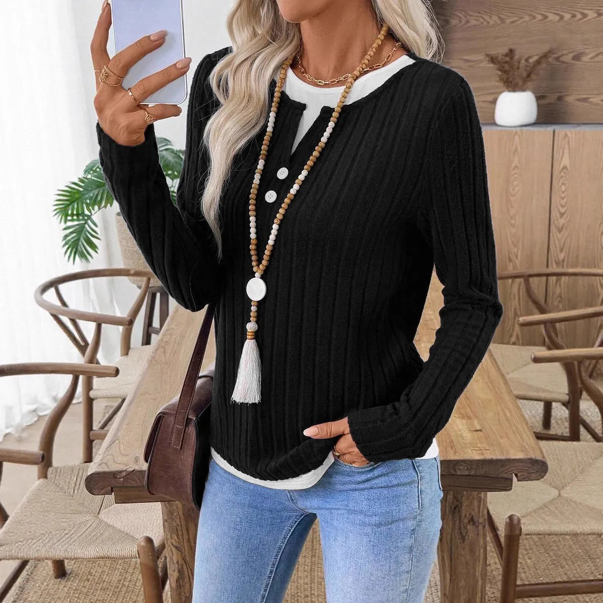 Women's black fake two-piece pullover sweater with button front and round neck on a hanger.