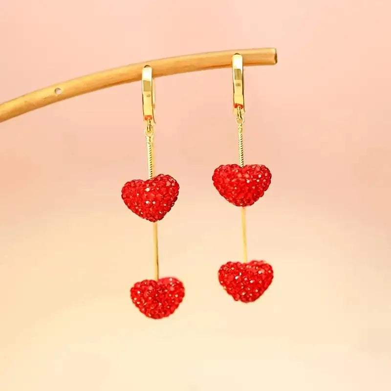 Red heart-shaped long earrings for women made of alloy with an electroplated finish, shown against a neutral background.