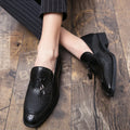 Men's black pointed toe slip-on shoes with a decorative tassel on the front.