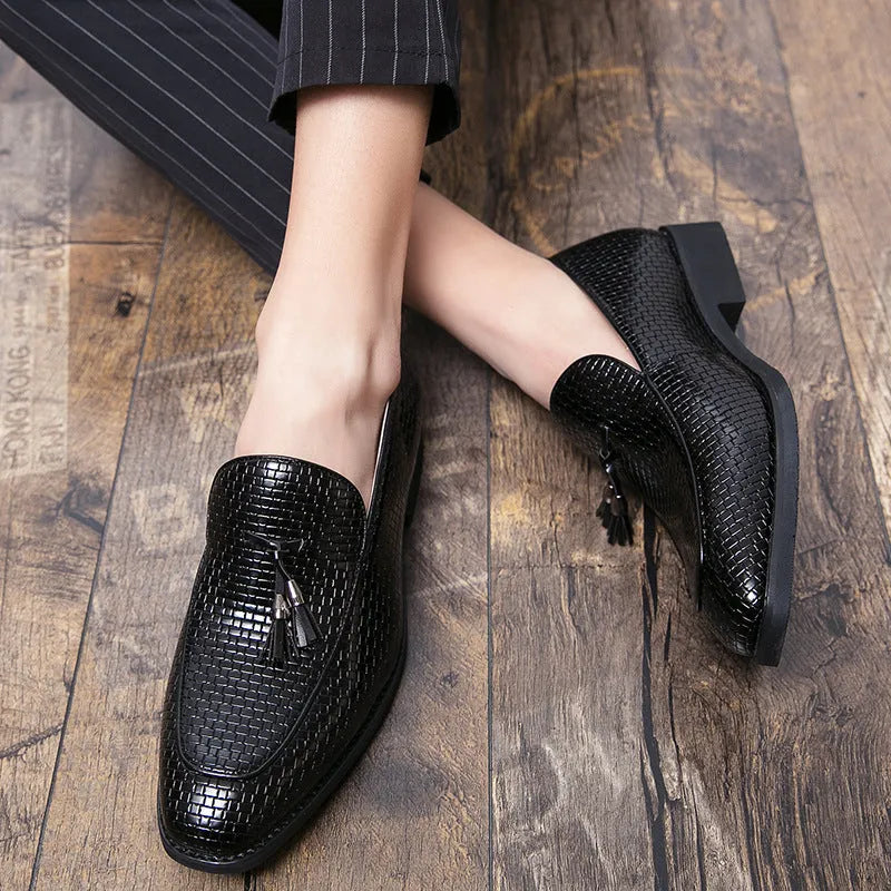 Men's black pointed toe slip-on shoes with a decorative tassel on the front.