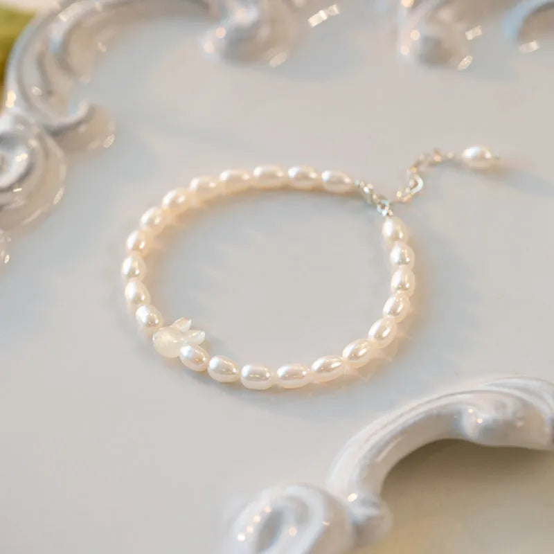 White shell small rice-shaped beads pearl elastic string rabbit bracelet 16cm handmade 925 silver on white background
