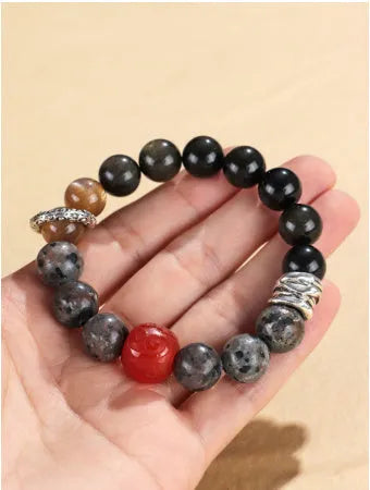 Gold obsidian flame stone and red agate unisex bracelet on a neutral background