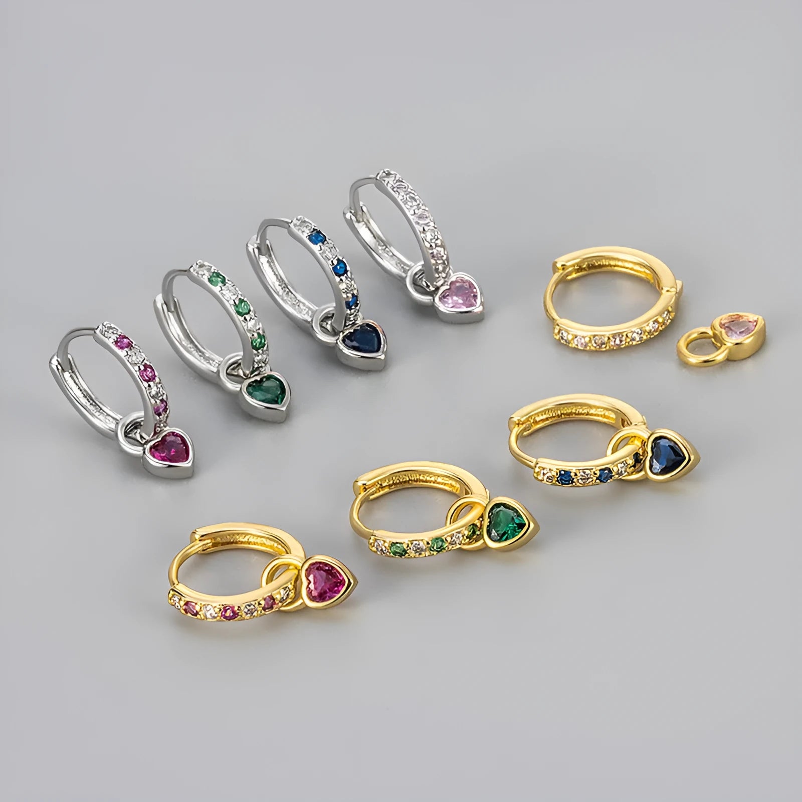 Women's heart-shaped clip-on earring with coloured gemstone centre on a gold-coloured metal setting.