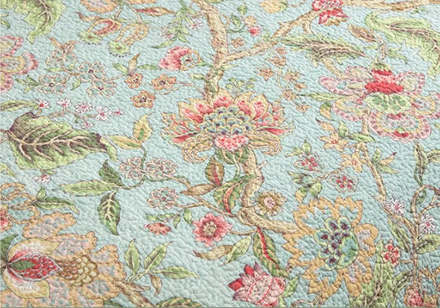 Blue American floral and bird pattern on a pure cotton quilt set with pillowcases, laid on a bed.