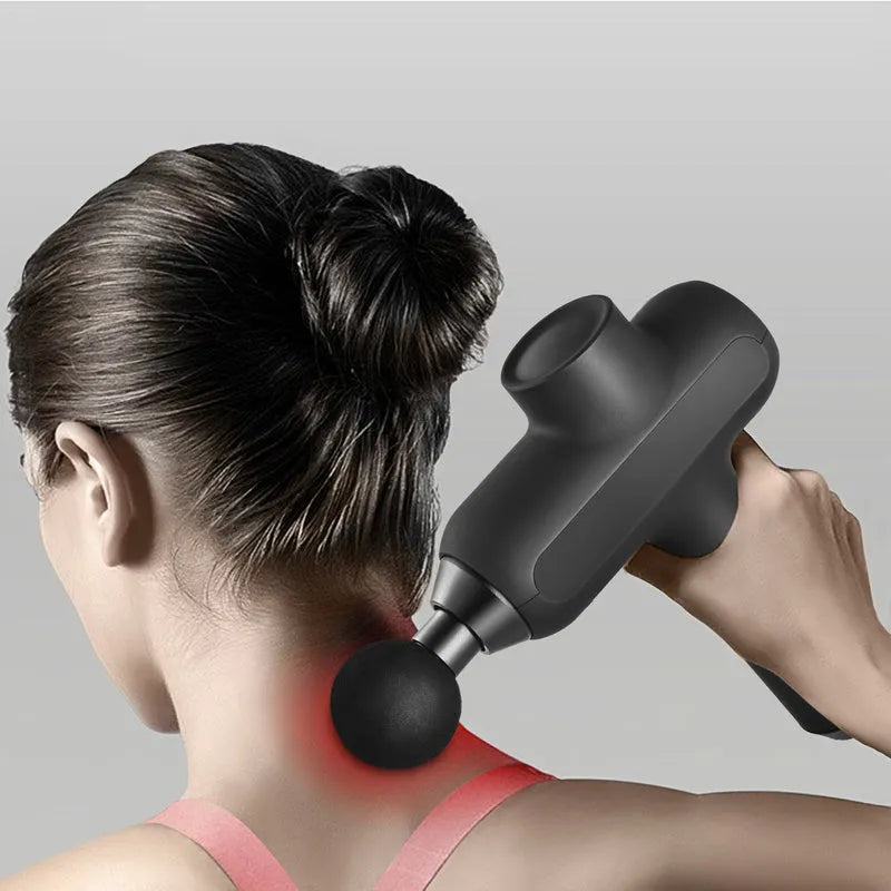 Handheld black muscle percussion massager with six different coloured attachment heads on a table.