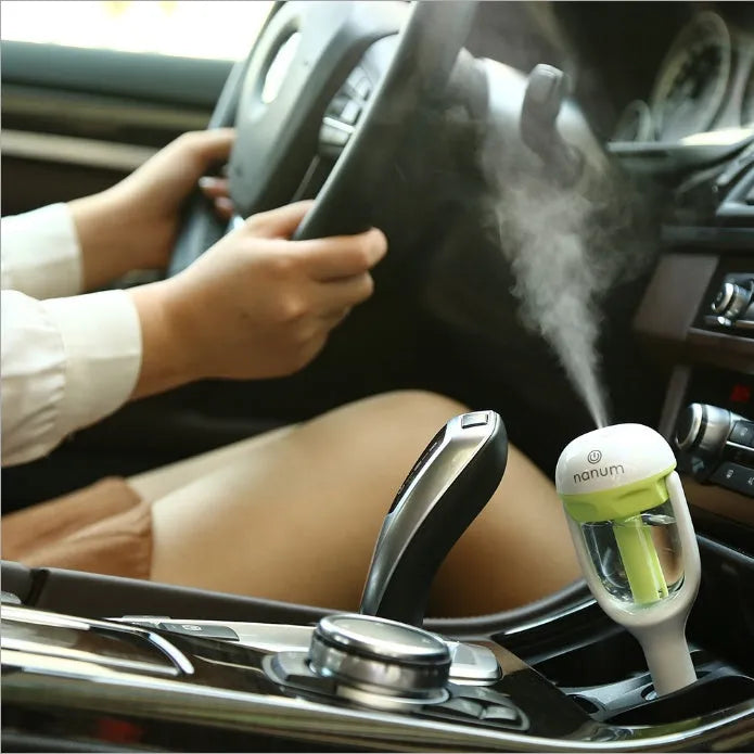 Compact blue car humidifier diffuser with rotating nozzle on a car dashboard