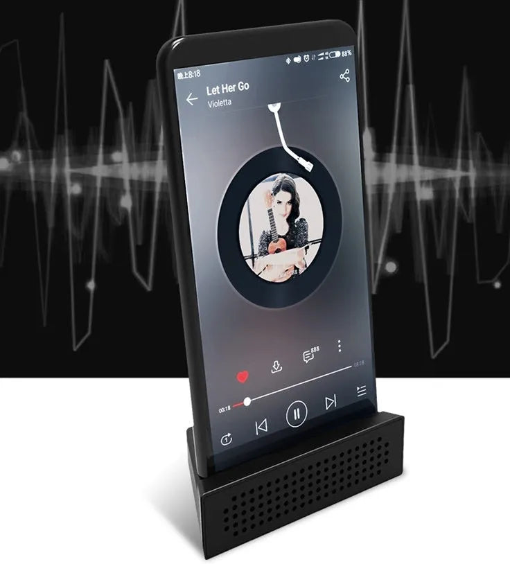 A small, coloured plastic mobile phone amplifier bracket holding an iPhone on a desktop.