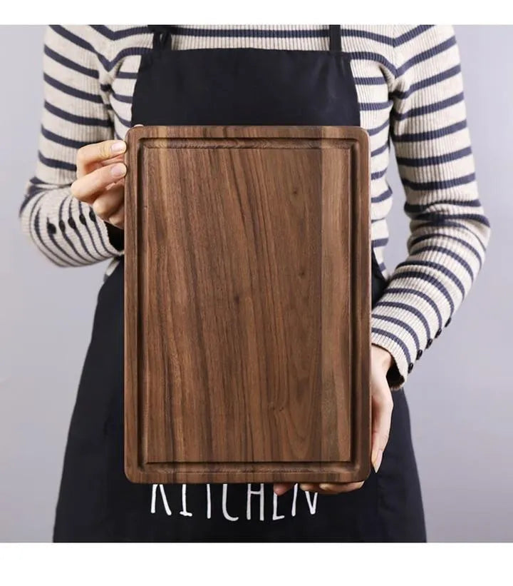 Black walnut wood double-sided cutting board with juice groove and side handle on kitchen counter