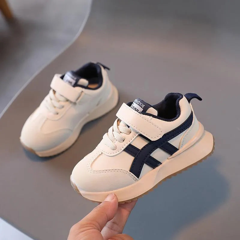 Children's white velcro sneaker with synthetic leather upper and rubber sole on a neutral background.
