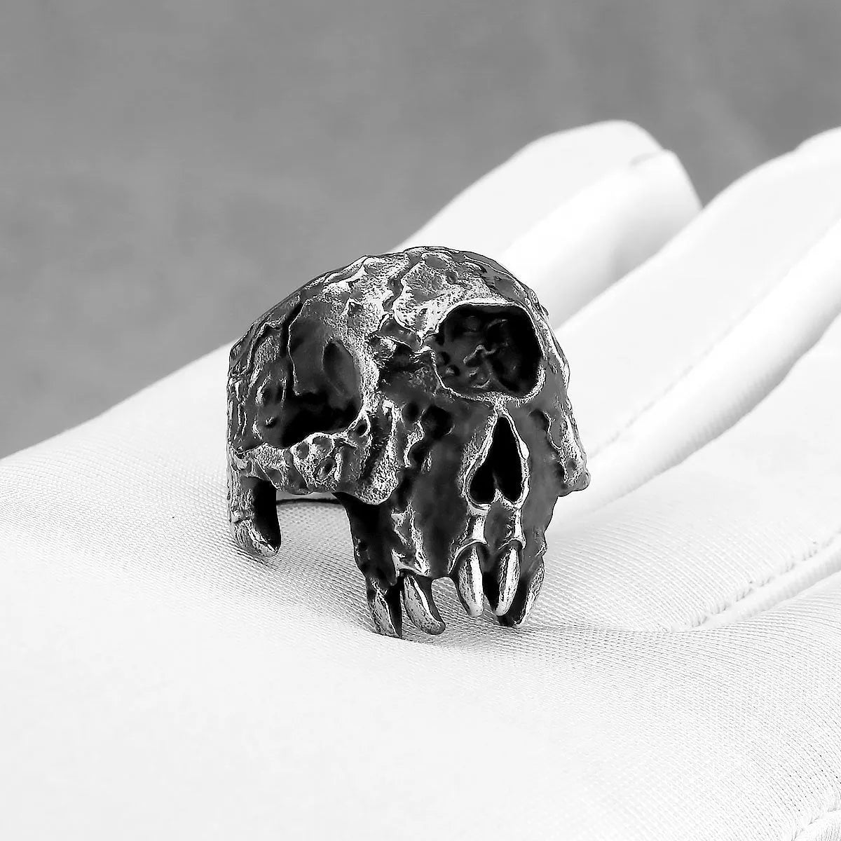 Close-up of a silver-toned alloy ring featuring a detailed one-eyed skull design on a finger.