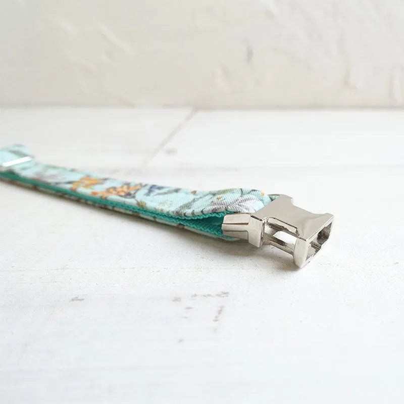 Green adjustable pet collar made of cloth and webbing on a neutral background