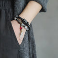 Ethnic style black hair crystal bracelet with white crystal tassel and bending lacing closure on plain background