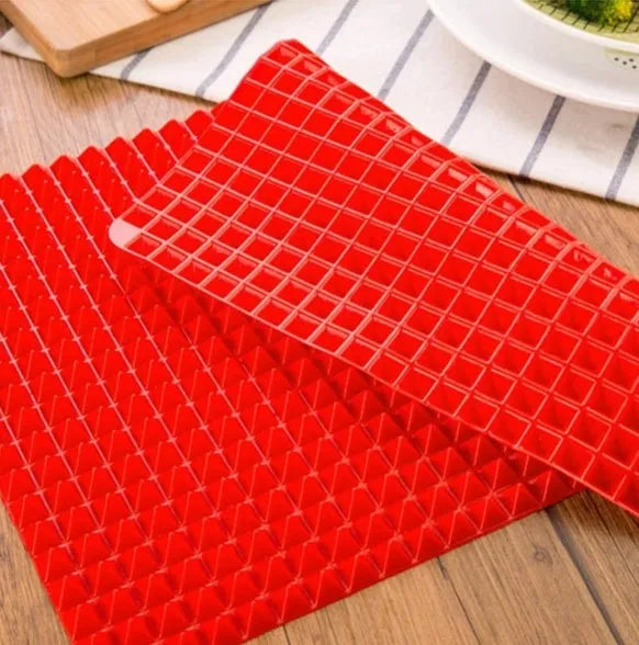 Red non-stick silicone pyramid cooking mat with grid on a baking tray for oven or BBQ use