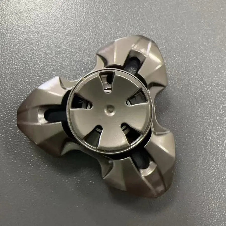 Alloy decompression fingertip gyro toy in gun colour finish on a dark background