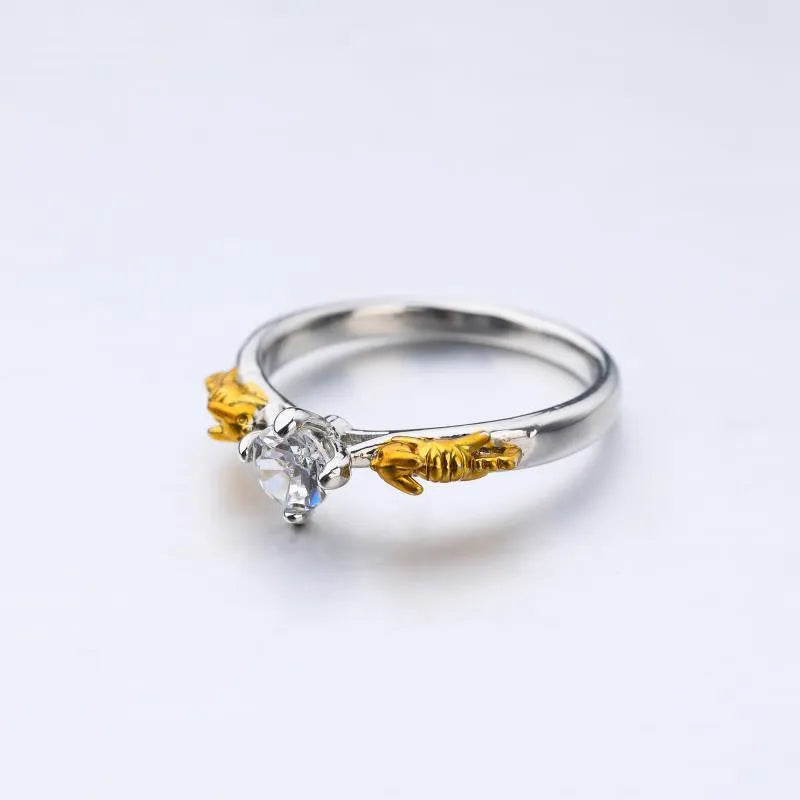 Copper crown ring with crystals in a black gold finish, shown on a finger.
