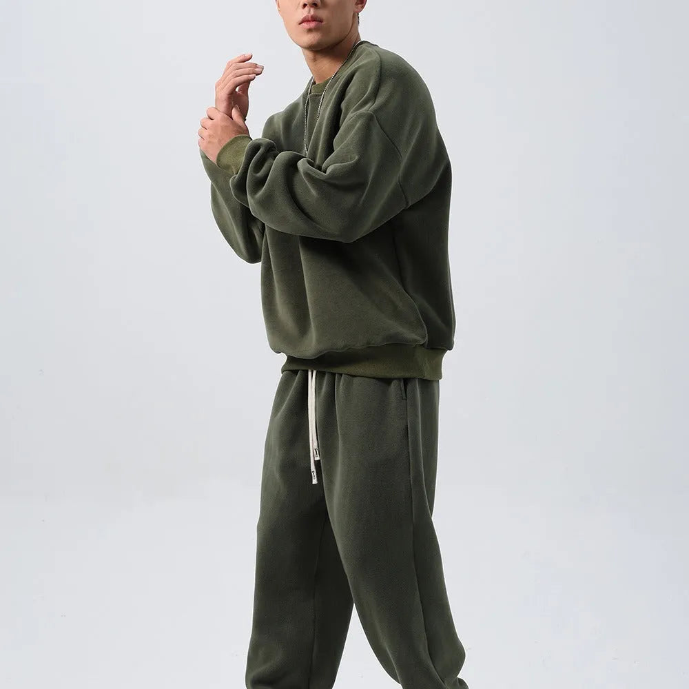 Man wearing a loose-fit black polar fleece jacket and matching trousers, a two-piece winter sports suit.