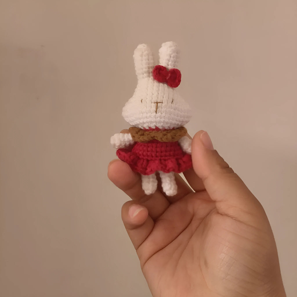 Hand-crocheted wool rabbit key chain pendant with key chain attachment on a soft surface