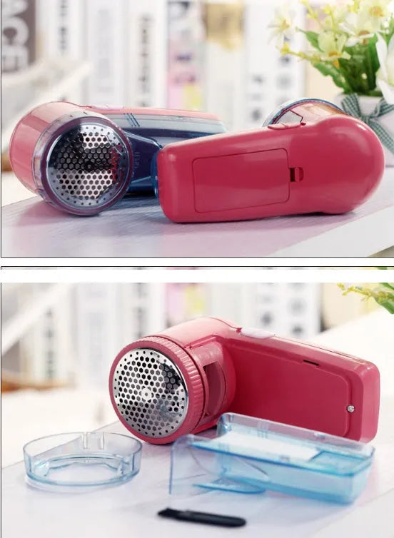 Compact white electric lint remover for clothing on a table next to a grey sweater.