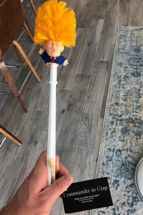 Yellow plastic Donald Trump toilet brush with handle slot, 40cm length, on white background