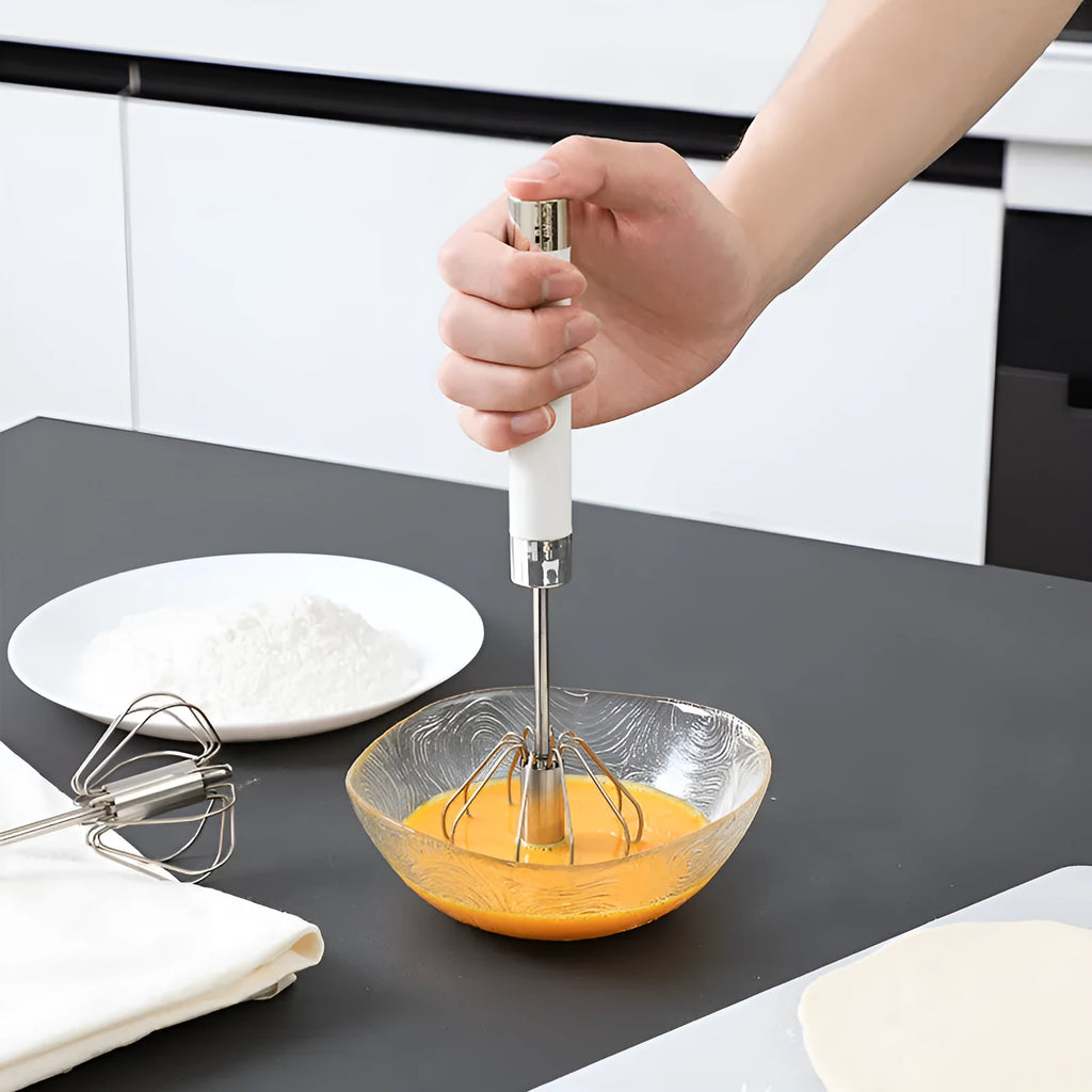 Semi-automatic stainless steel egg beater whisk with hand pressure rotating handle, silvery colour, on white background