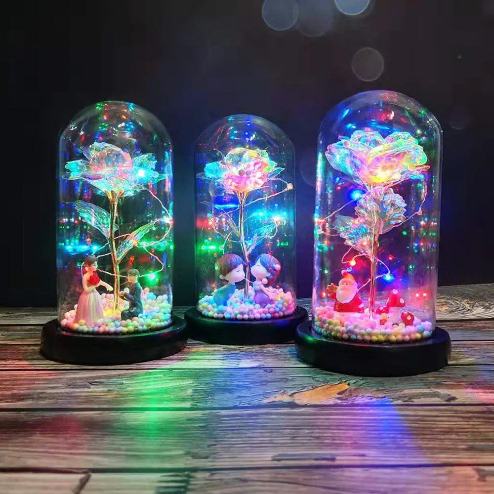 Artificial gold rose in glass flask with LED lights on black base, 20cm tall