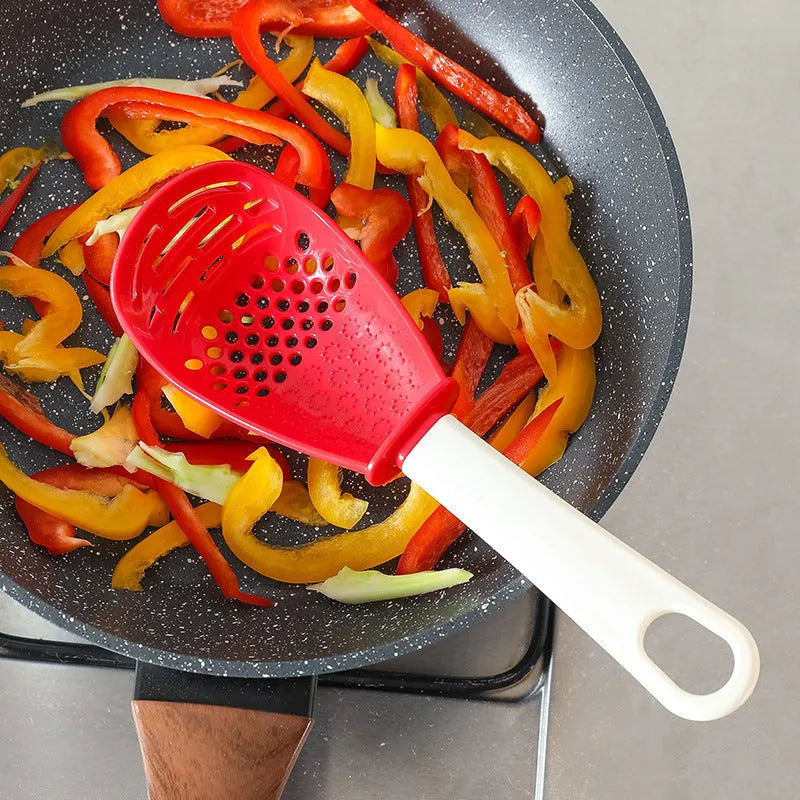 Multifunctional slotted grinding cooking spoon in red plastic with half-enclosed head and serrated edge