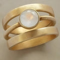 Gold-plated geometric ring with hollow micro-inlaid white chalcedony gemstone and line pattern design