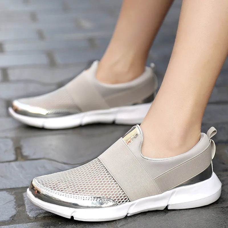Blue low-top women's mesh sneakers with a casual design on a hard floor surface.