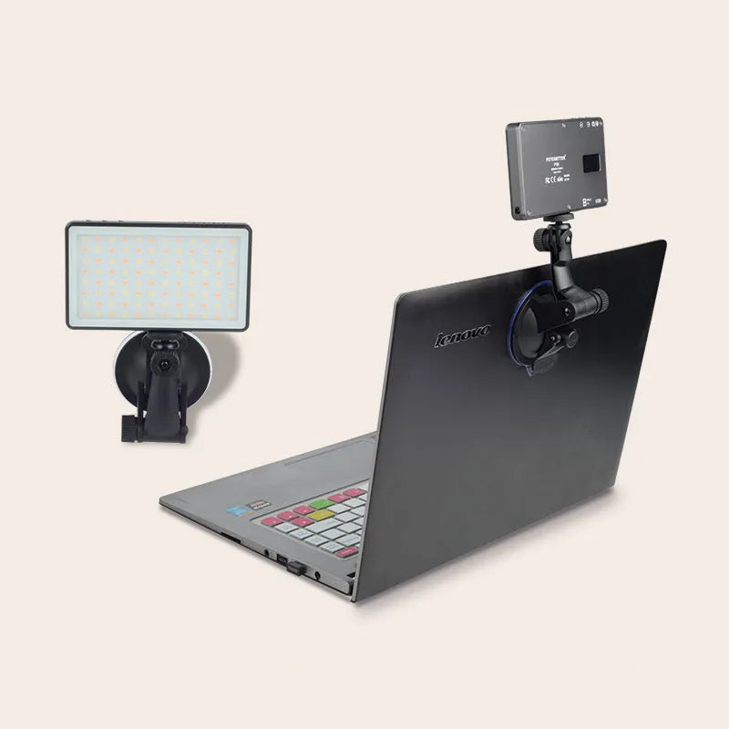 Black aluminium alloy portable LED ring light for laptop video conferencing on a desk.