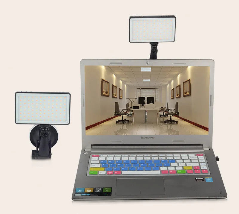 Black aluminium alloy portable LED ring light for laptop video conferencing on a desk.