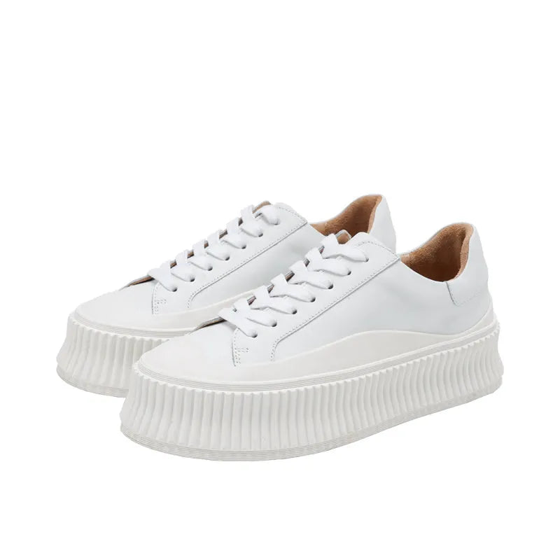 Women's white suede trainers with thick soles, cross-binding detail, and back lacing.