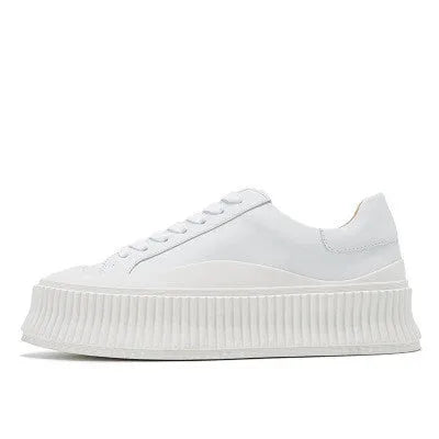Women's white suede trainers with thick soles, cross-binding detail, and back lacing.