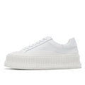 Women's white suede trainers with thick soles, cross-binding detail, and back lacing.