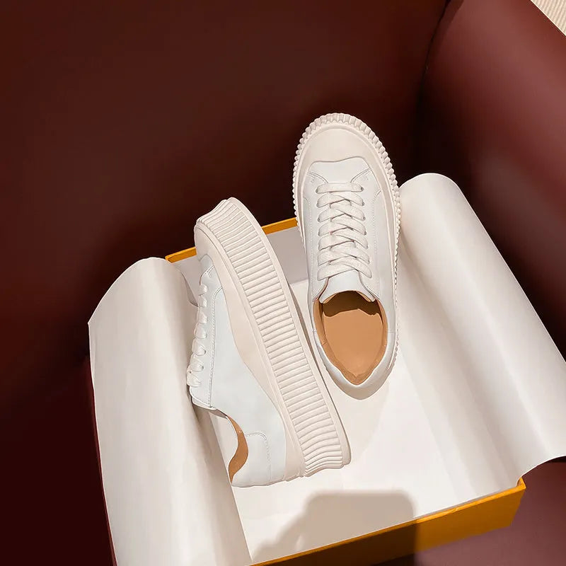 Women's white suede trainers with thick soles, cross-binding detail, and back lacing.